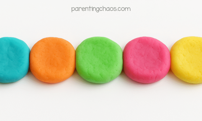Flattened neon playdough discs in a rainbow row, ready for sensory play or black light fun.