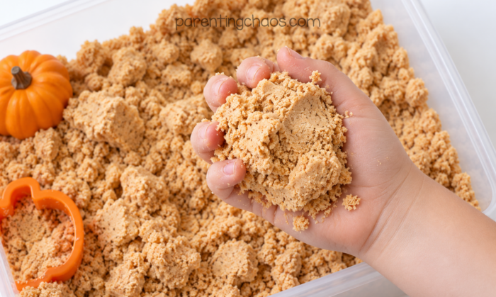 Child playing with pumpkin moon sand sensory bin