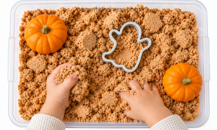 Child playing with pumpkin moon sand sensory bin
