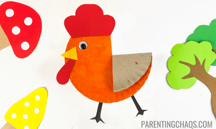 Bright and playful Little Red Hen paper plate craft featuring an orange-painted plate with a red comb, yellow beak, red wattle, googly eye, and brown wing, surrounded by colorful paper mushrooms and trees on a white background.