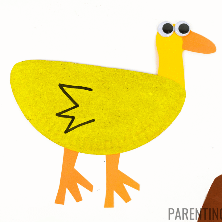 Easy paper plate duck craft for kids made with a yellow painted paper plate, orange paper legs and beak, googly eyes, and a black zigzag wing detail drawn with marker.