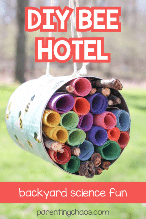 Hanging DIY bee hotel made from a decorated tin can filled with rolled paper and twigs for a kids’ science craft.