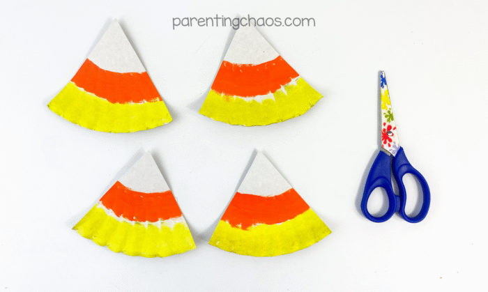 Painted paper plate cut into four candy corn triangles with scissors.