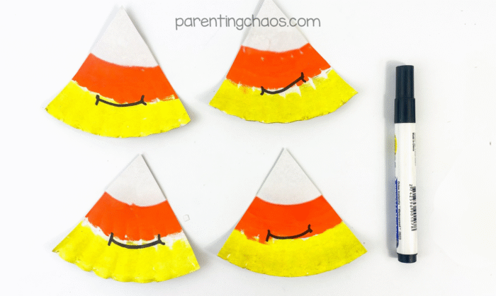 Candy corn paper plate pieces with smiling faces drawn in black marker.