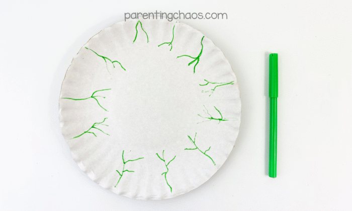 White paper plate with green marker veins drawn around the edges to create a spooky eyeball effect.