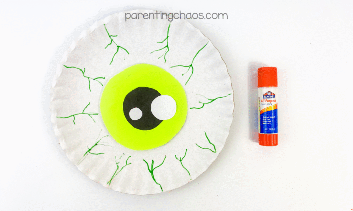 Green iris with black pupil glued to the center of the paper plate with green veins drawn around the edges.
