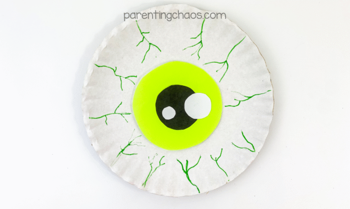 Finished eyeball paper plate craft with bright green iris and green marker veins for a spooky Halloween effect.
