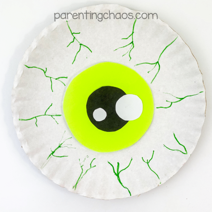 Finished eyeball paper plate craft with bright green iris and green marker veins for a spooky Halloween effect.