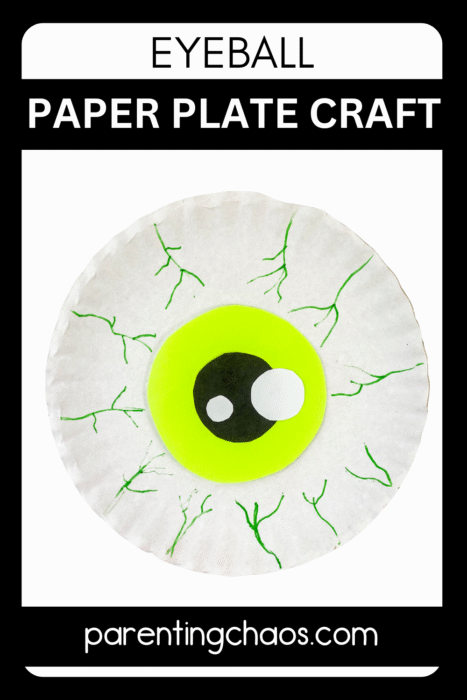 Close-up of a handmade paper plate eyeball craft with green iris, black pupil, and white highlights, surrounded by green veins on a white background.