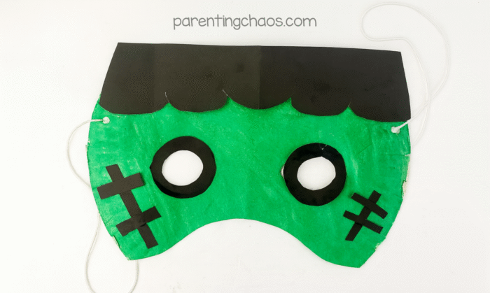 Finished Frankenstein paper plate mask with string tied and ready to wear, displayed on white background.