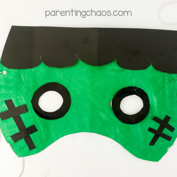 Finished Frankenstein paper plate mask with string tied and ready to wear, displayed on white background.