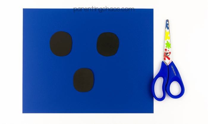 Three black oval shapes cut out for ghost’s eyes and mouth.