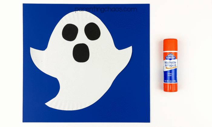 Paper plate ghost with black eyes and mouth glued on top.