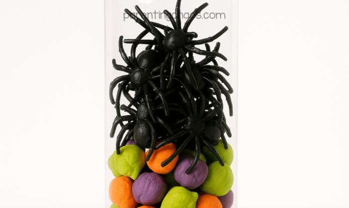 Plastic black spiders added on top of the colorful clay balls inside the sensory bottle, creating a layered Halloween look.