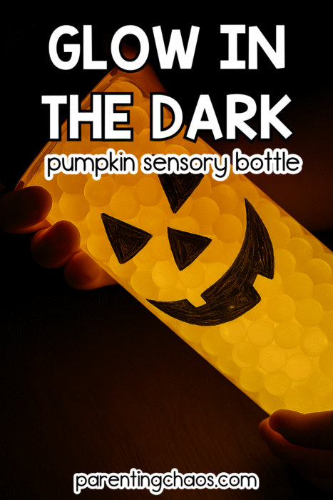 Close-up of a glowing pumpkin sensory bottle filled with orange water beads and a smiling jack-o’-lantern face drawn in black marker.
