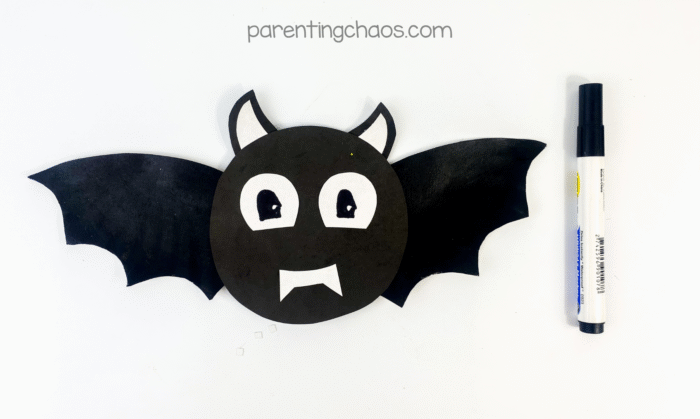 Black marker adding details to the eyes on the finished bat face.