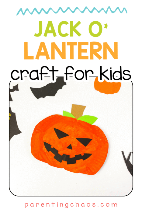 Jack-O’-Lantern paper plate craft for kids displayed on a white table with paper bats and mini pumpkins scattered around. Hands-on Halloween craft for toddlers and preschoolers.