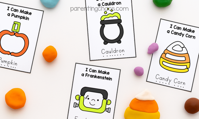 Overhead view of Halloween playdough task cards for pumpkin, cauldron, Frankenstein, and candy corn. Bright playdough pieces in orange, yellow, green, purple, and white are scattered around each card.