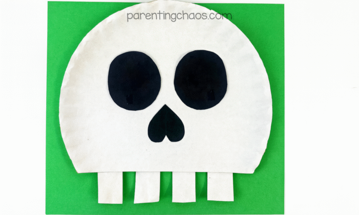 Completed skull paper plate craft against a green background.