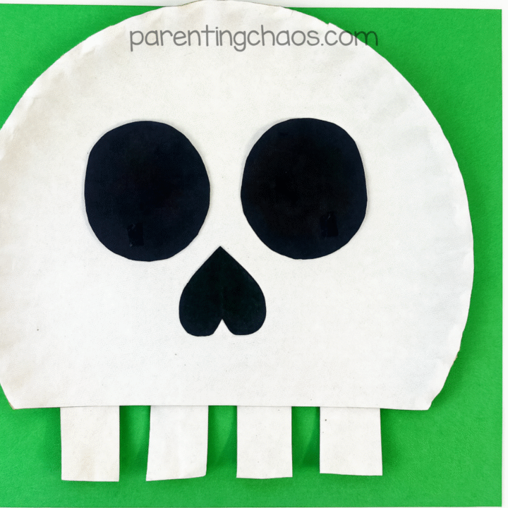 Completed skull paper plate craft against a green background.