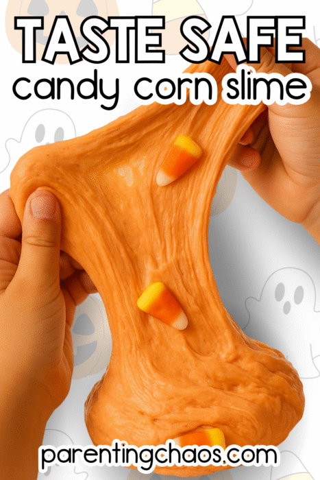 Hands stretching soft orange candy corn slime with candy pieces mixed in.