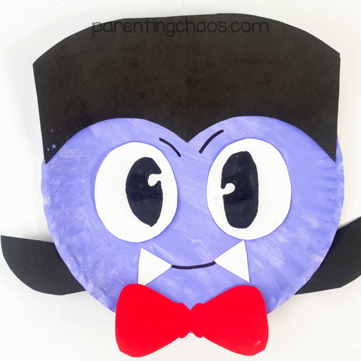 Completed vampire paper plate craft with black hair, big eyes, a red bow tie, and white fangs.