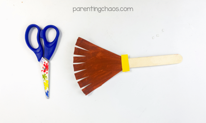 Paper plate broom with bristles cut and spread apart.