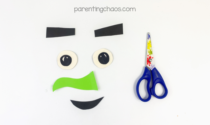 Witch face parts cut out — eyebrows, eyes, mouth, and green nose — ready to assemble.