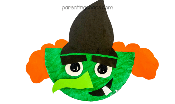Finished paper plate witch craft with bright green face, orange hair, and black hat.