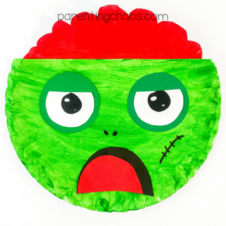 Finished paper plate zombie craft with bright green face and red brain.