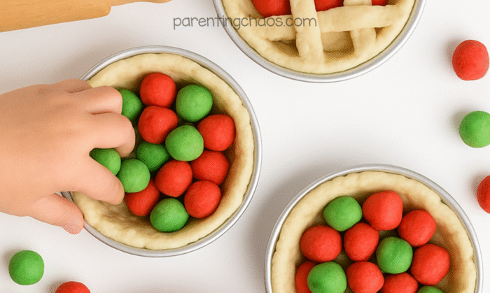 Kids playing with mini pies made from apple pie playdough, filling the crusts with red and green dough “apples.”