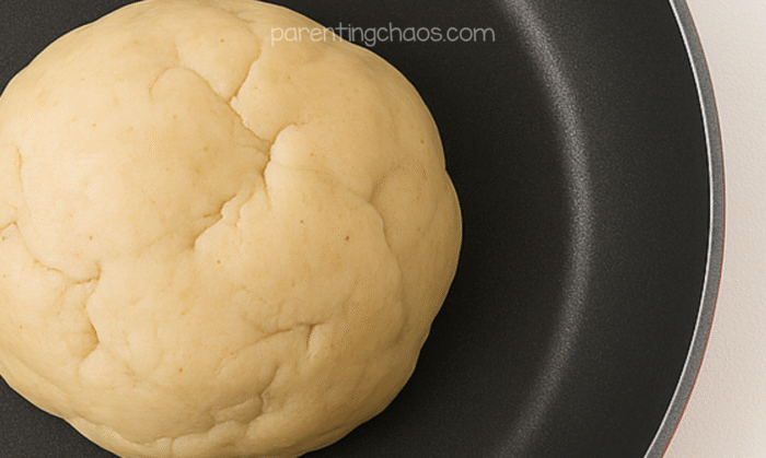 A smooth ball of cooked apple pie playdough cooling in a pan before coloring.