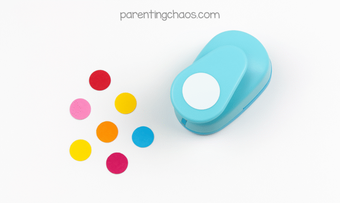 Colorful paper circles punched out using a blue circle punch tool, to be used as ornaments in the paper plate Christmas tree craft for kids.