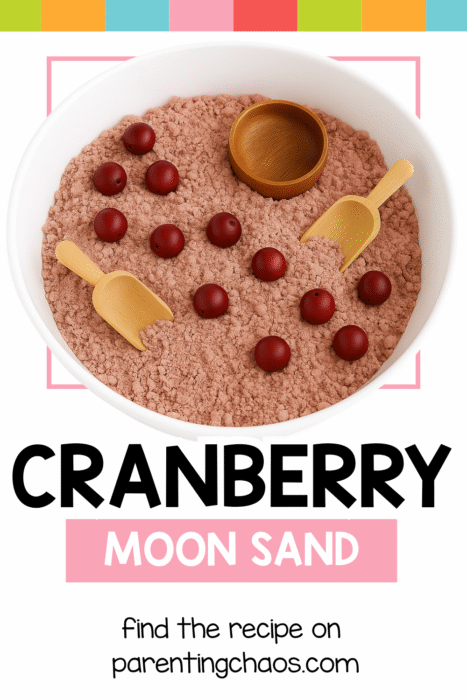 A white sensory bin filled with cranberry-colored moon sand, red wooden balls, and two small wooden scoops. Text on the image reads “Cranberry Moon Sand. Find the recipe on parentingchaos.com.”