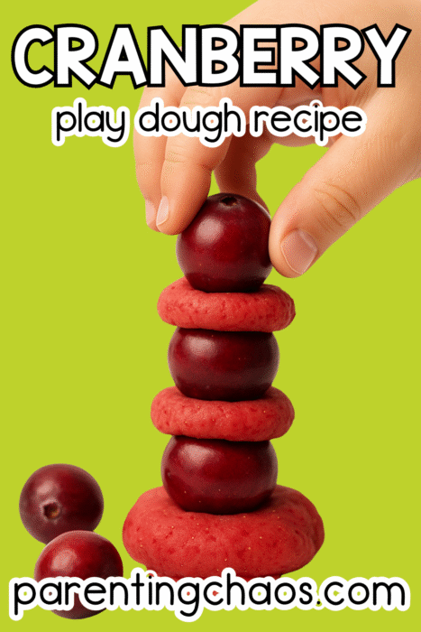 Child stacking cranberries and red play dough pieces to make a fun sensory tower.