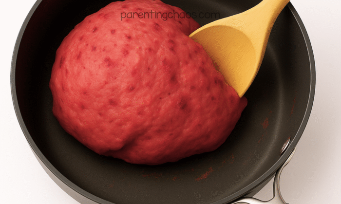 Cooked cranberry playdough forming into a soft ball in the saucepan.