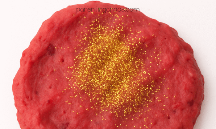 Freshly made cranberry playdough topped with gold glitter before kneading.