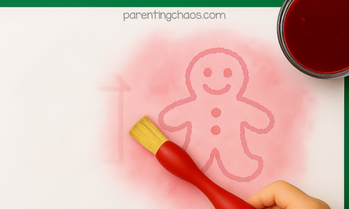 Child painting cranberry juice over the paper to reveal a hidden gingerbread man and house drawn in invisible ink.