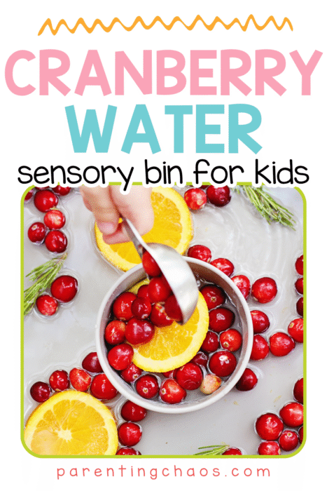 Child scooping floating cranberries and orange slices in a water sensory bin.