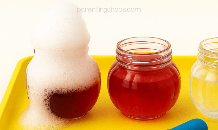 Close-up of a foaming jar overflowing with bubbles after vinegar reacts with baking soda and cranberry juice.