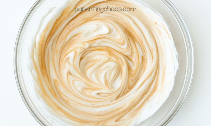 Bowl of partially mixed glue, shaving cream, and foaming hand soap showing light tan and white swirls before adding spices.