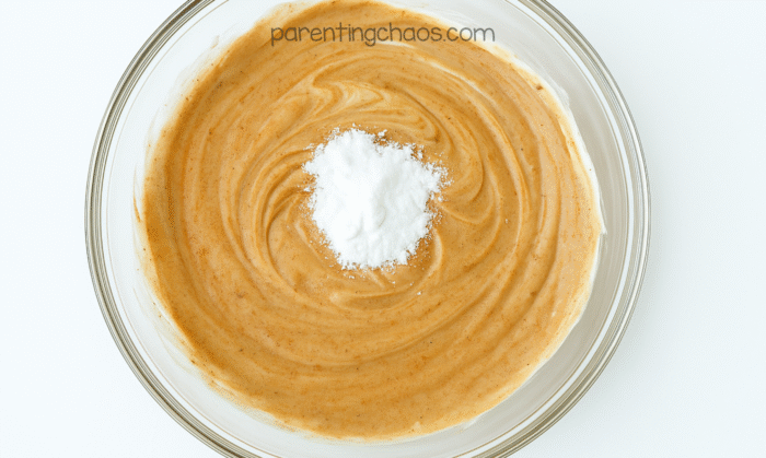 Baking soda piled in the center of the gingerbread-colored slime mixture before stirring.