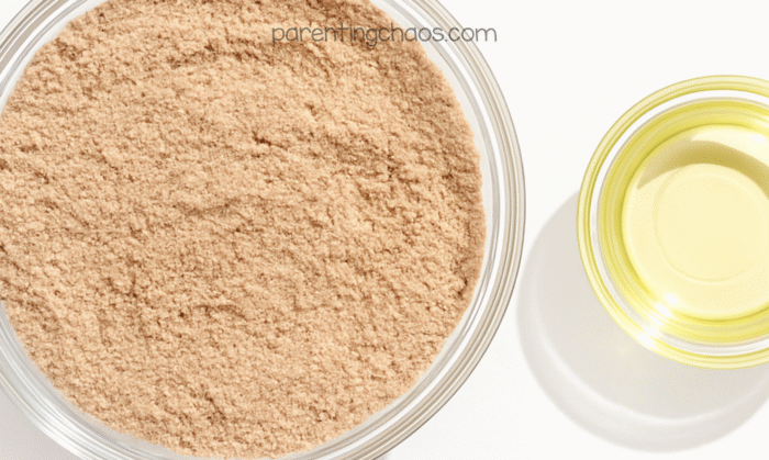 Flour and spices mixed together into a light brown gingerbread-colored base beside a small bowl of oil.