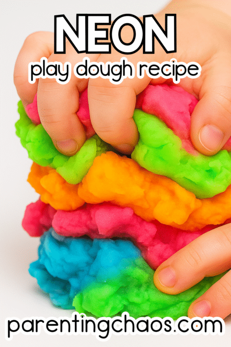 Child squeezing and mixing soft neon play dough in bright pink, orange, green, and blue — fun sensory activity idea from Parenting Chaos