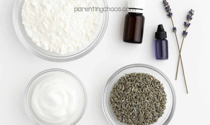 Overhead view of ingredients for lavender conditioner playdough — cornstarch, hair conditioner, dried lavender buds, essential oil bottles, and lavender sprigs on a white background.