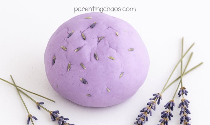 Finished ball of lavender conditioner playdough topped with dried lavender buds, surrounded by lavender sprigs.