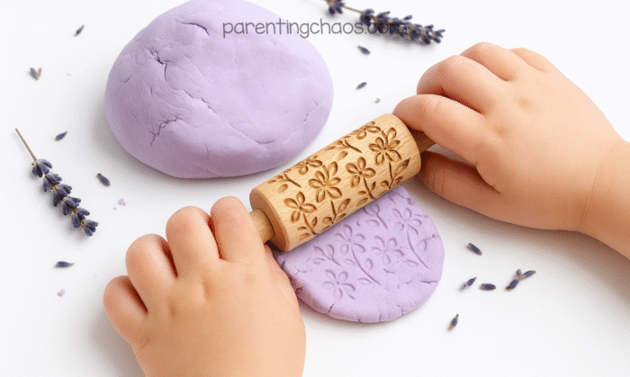 Child rolling out lavender playdough with a wooden embossed flower rolling pin, lavender sprigs scattered around.