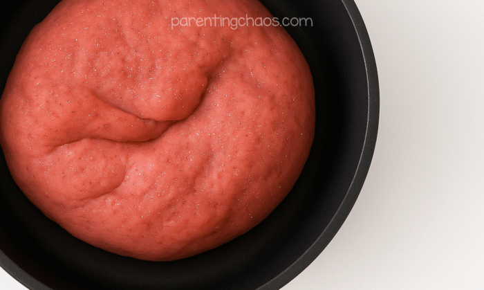 Freshly cooked pink peppermint playdough cooling in a pan, showing a smooth, soft texture.