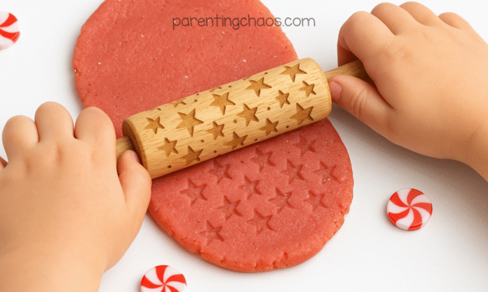 Child using a wooden star-patterned rolling pin to flatten peppermint playdough with embossed star prints.