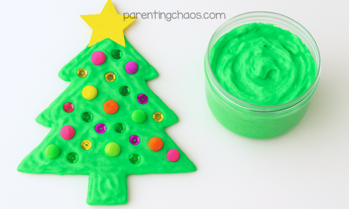 Finished green puffy paint Christmas tree decorated with pom poms, sequins, and a yellow star beside a jar of leftover green puffy paint.